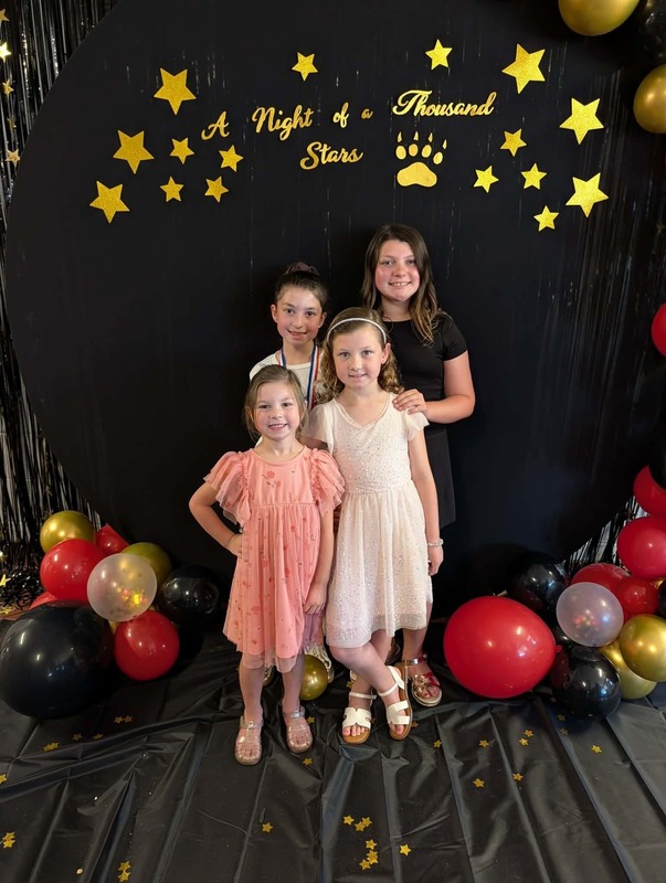 Family of four posing in front of black backdrop that says "Night of a Thousand Stars".