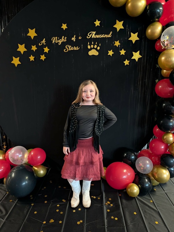 Student posing in front of black backdrop that says "Night of a Thousand Stars".