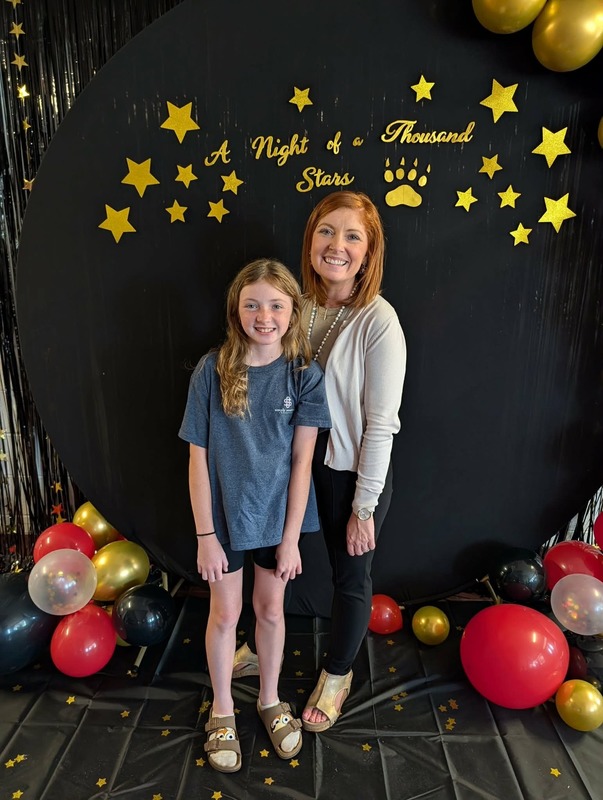 Student and staff posing in front of black backdrop that says "Night of a Thousand Stars".