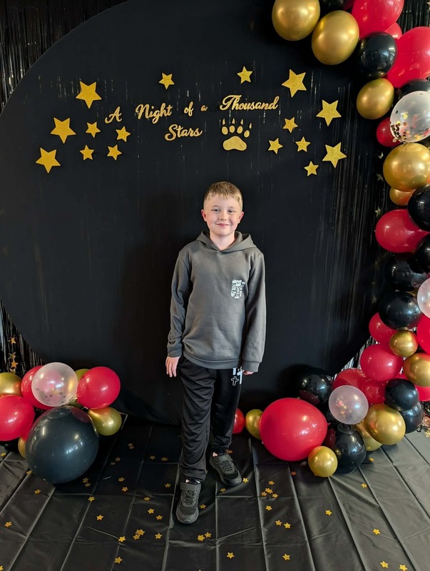 Student posing in front of black backdrop that says "Night of a Thousand Stars".