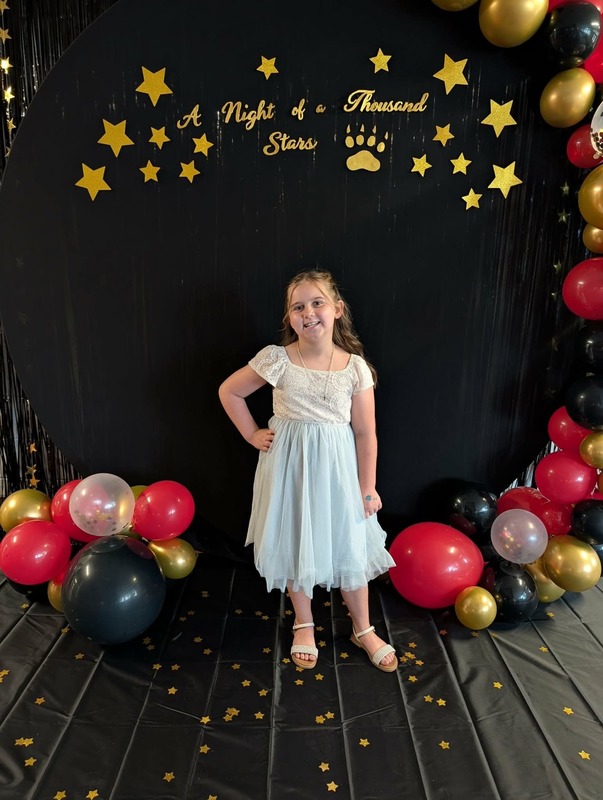 Student posing in front of black backdrop that says "Night of a Thousand Stars".