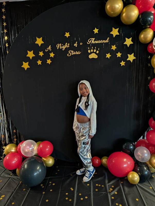 Student posing in front of black backdrop that says "Night of a Thousand Stars".