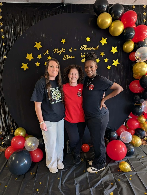 Three staff members posing in front of black backdrop that says "Night of a Thousand Stars".