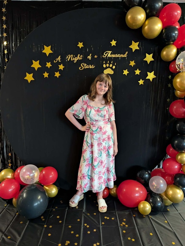 Student posing in front of black backdrop that says "Night of a Thousand Stars".