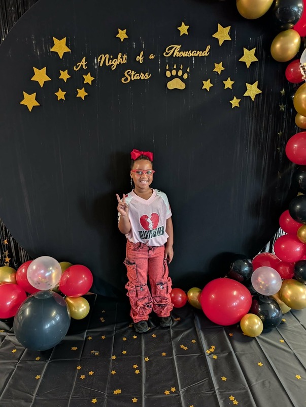 Student posing in front of black backdrop that says "Night of a Thousand Stars".