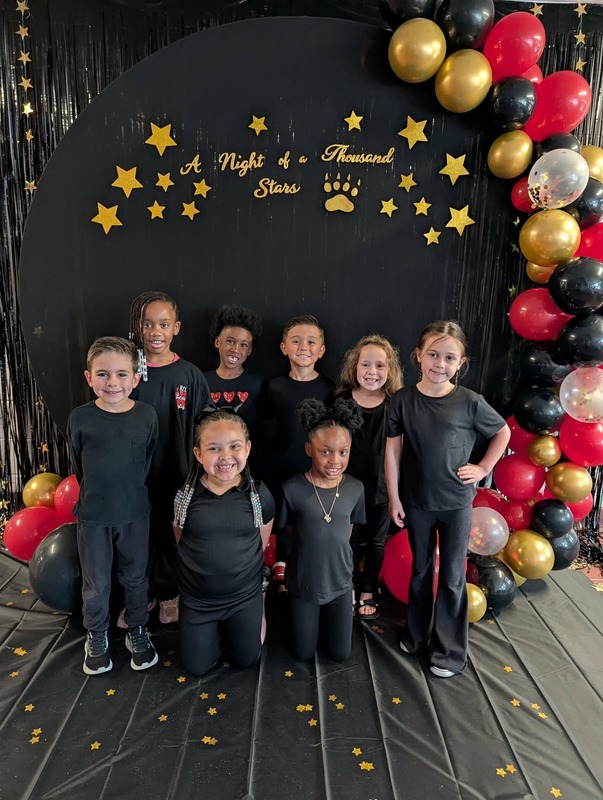 Students posing in front of black backdrop that says "Night of a Thousand Stars".