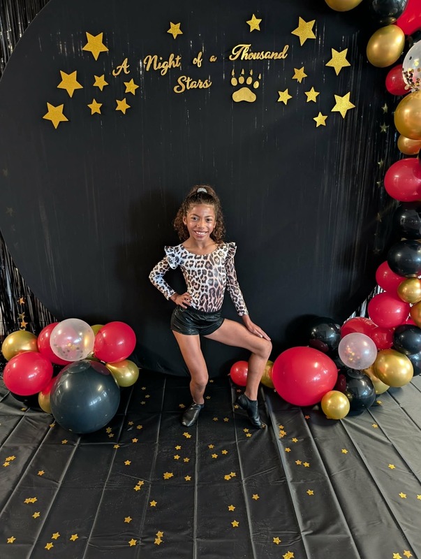 Student posing in front of black backdrop that says "Night of a Thousand Stars".