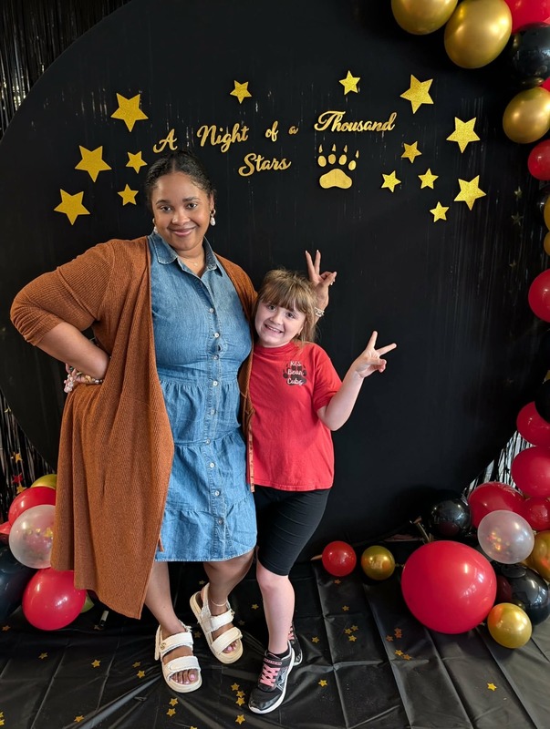 Student qand staff posing in front of black backdrop that says "Night of a Thousand Stars".