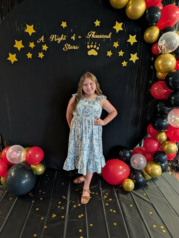 Student posing in front of black backdrop that says "Night of a Thousand Stars".