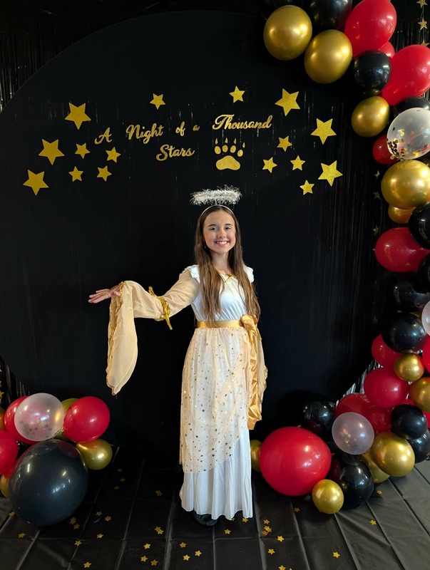 Student posing in front of black backdrop that says "Night of a Thousand Stars".