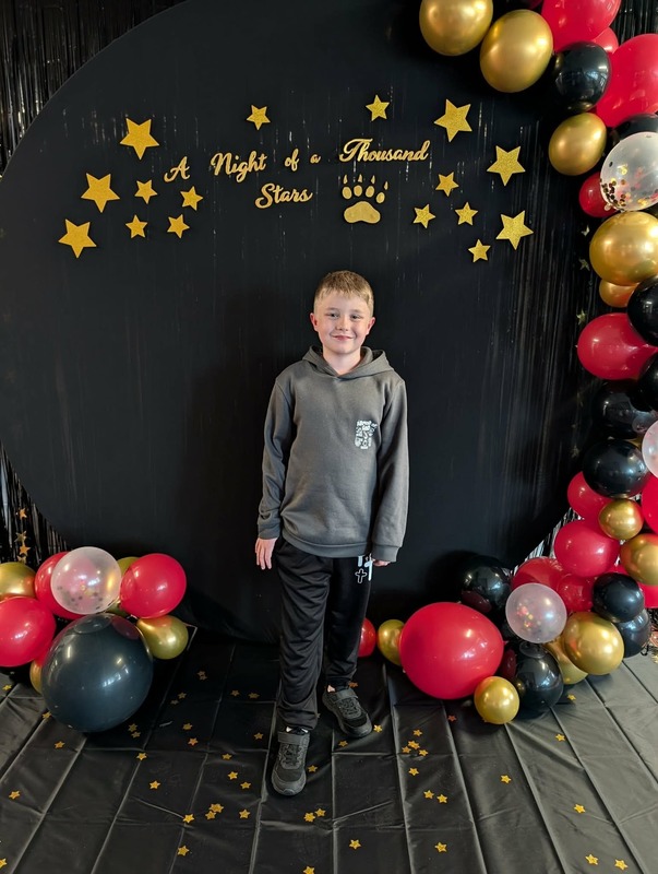 Student posing in front of black backdrop that says "Night of a Thousand Stars".