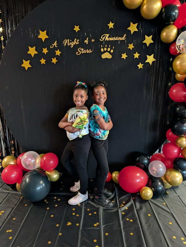 Students posing in front of black backdrop that says "Night of a Thousand Stars".