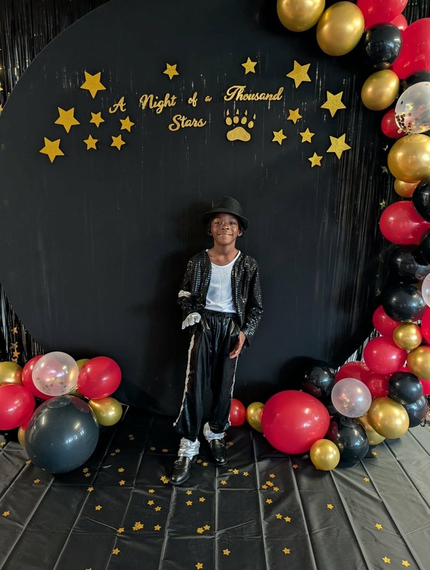 Student posing in front of black backdrop that says "Night of a Thousand Stars".