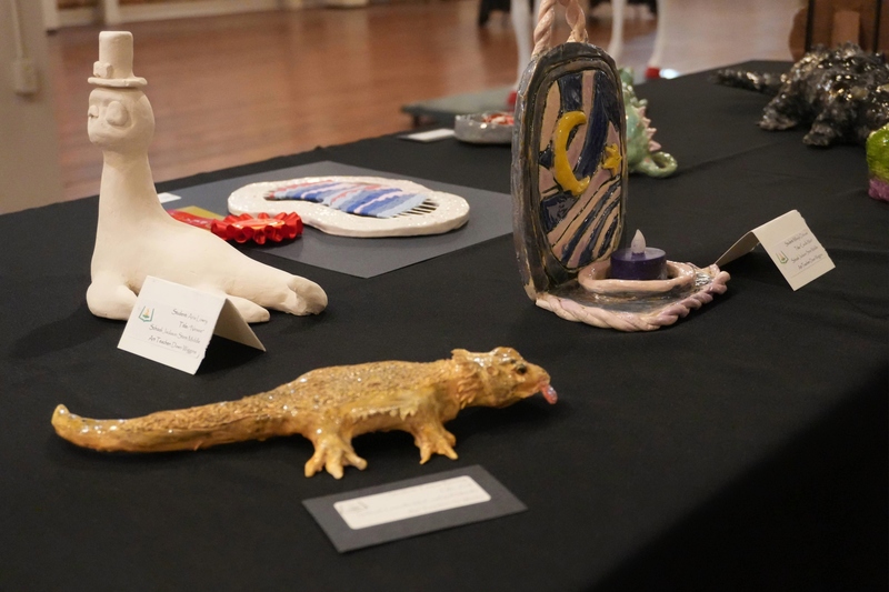 Ceramic art pieces on table including a lizard and moon.