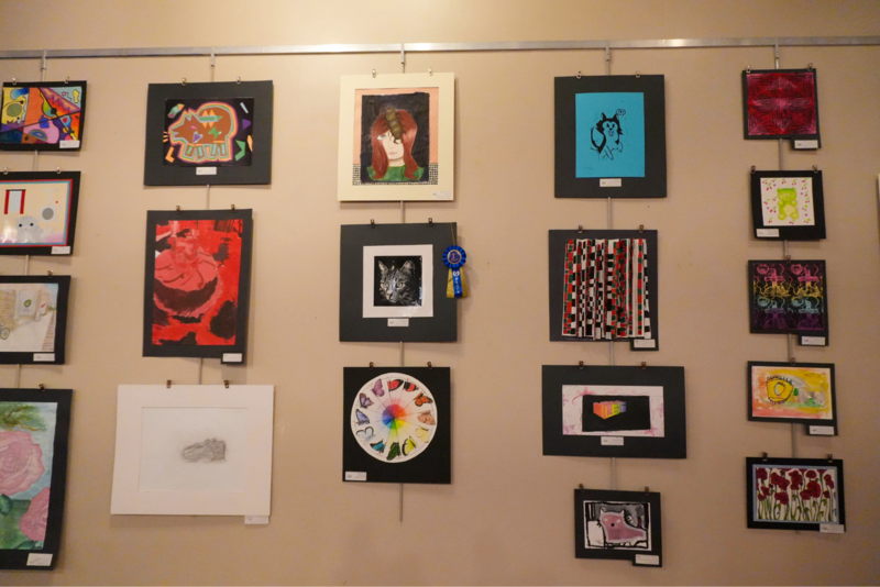 Wall containing multiple art pieces hung on the wall.
