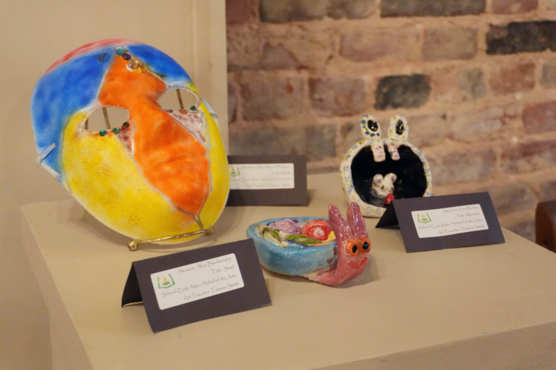 3D art including ceramic snail bowl and colorful mask.