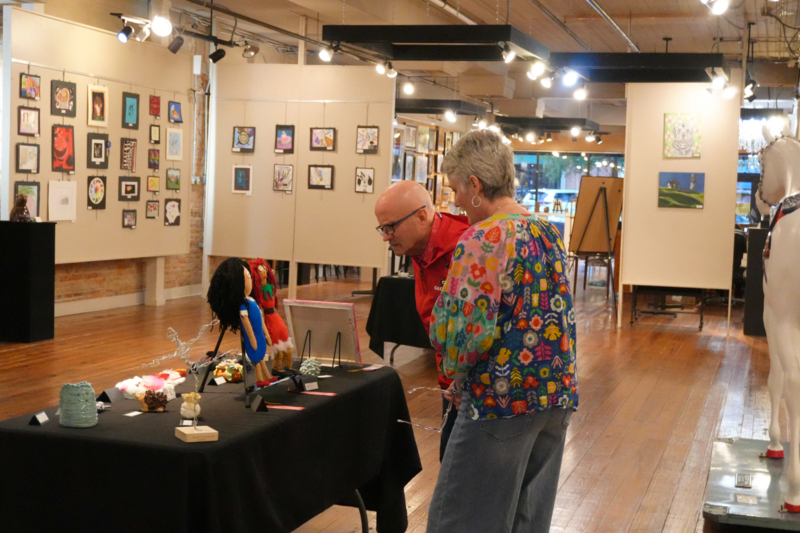 District leadership looking at student artwork displayed on table.
