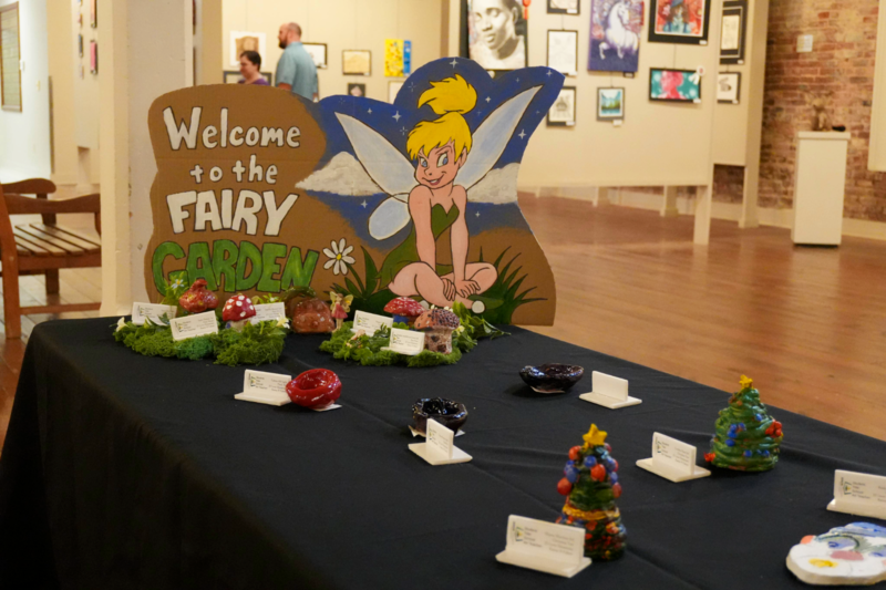 Ceramic art displayed on table with tinkbell painted on carboard introducing the theme of fairy garden.
