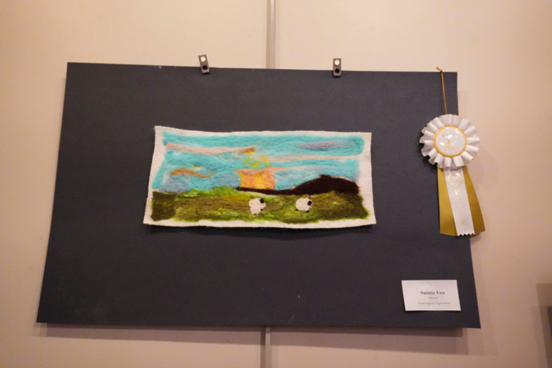 Wool art depicting colorful field with two sheep.
