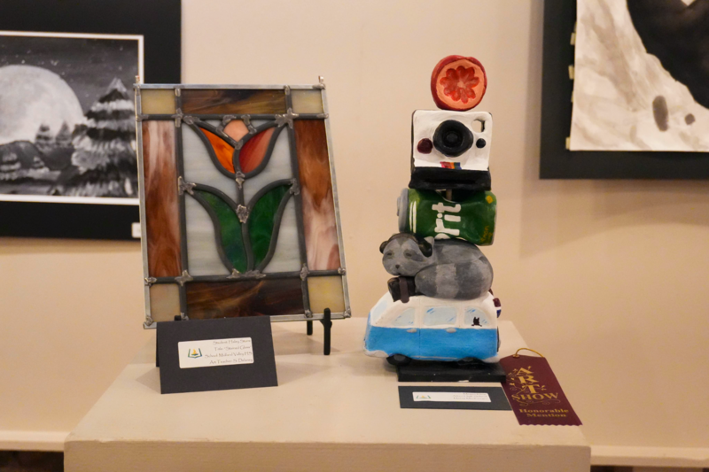 Stained glass and ceramic art of flower and camera.