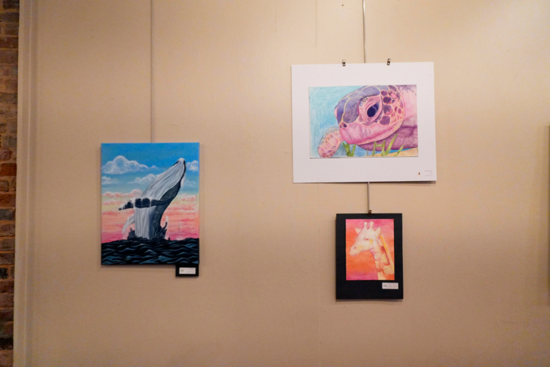 Wall art with pastel colors of a whale, sea turtle, and  giraffe.