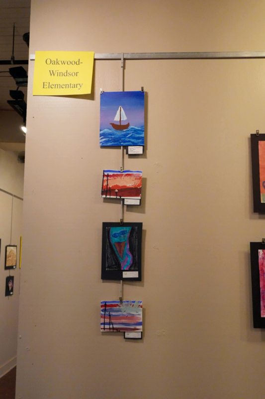 Elementary art of boat and landscpaes hanging on wall.