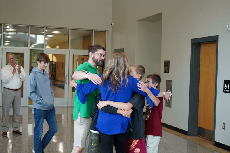 Teacher hugging family.