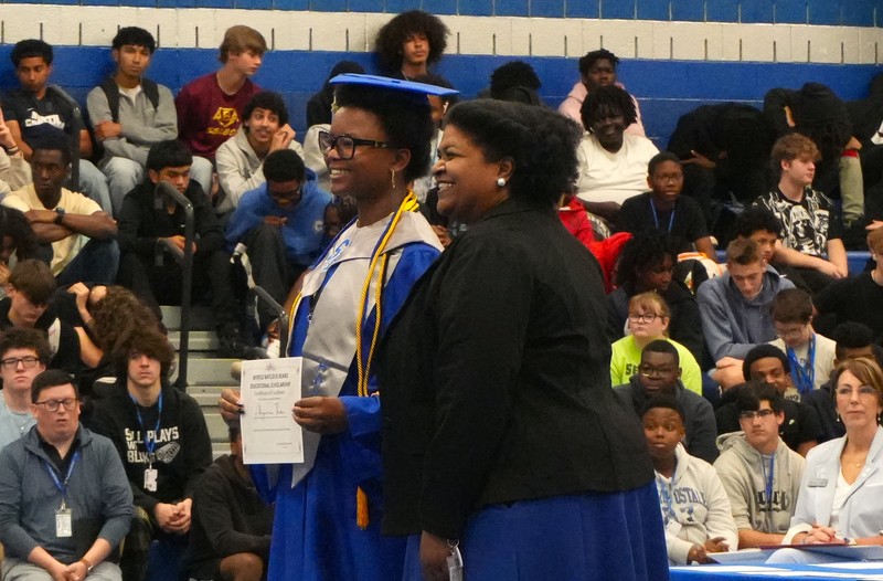 A student poses with a scholarship certificate.