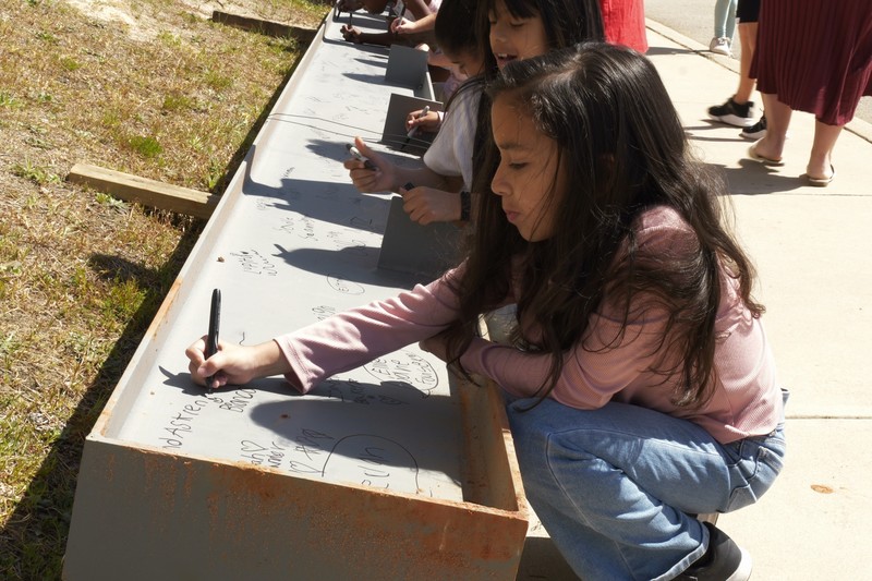 A student signing the beam.