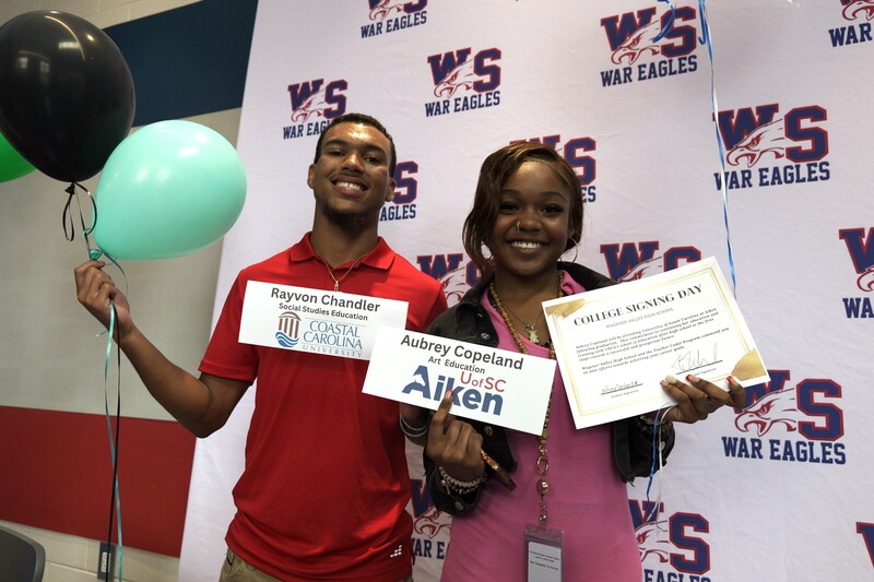 Two students poses with nameplate and certificate.