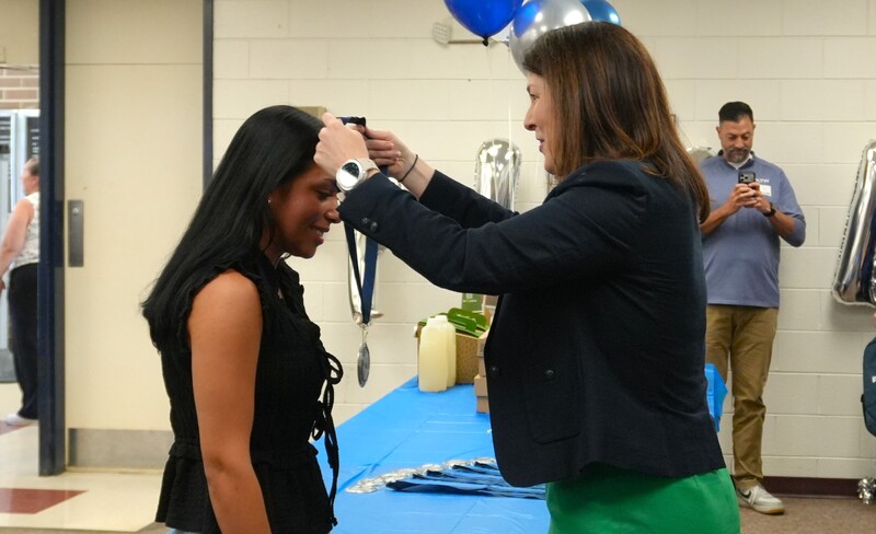 A student is being honored with a medal for her community outreach.
