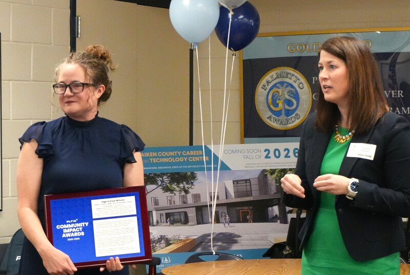 Dr. Palladino and Katie Minihan stand together with a Project Lead the Way Community Impact Award plaque.
