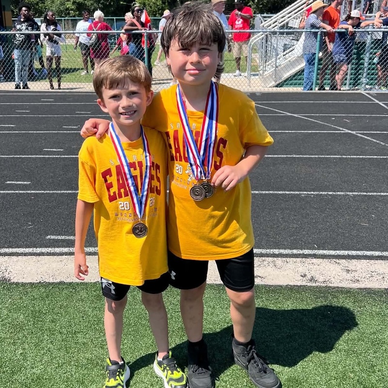 Two boy wearing medals stand arm in arm.