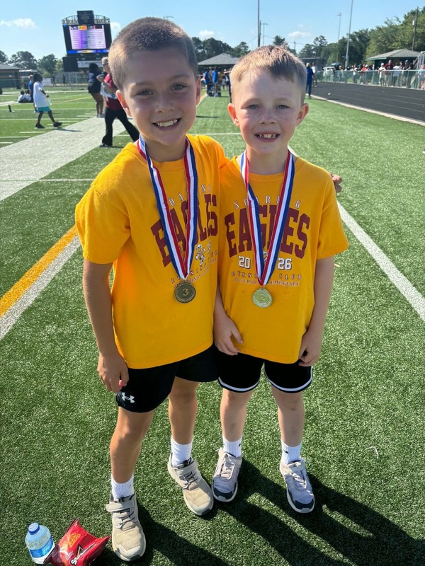 Two boys wearing medals stand arm in arm.