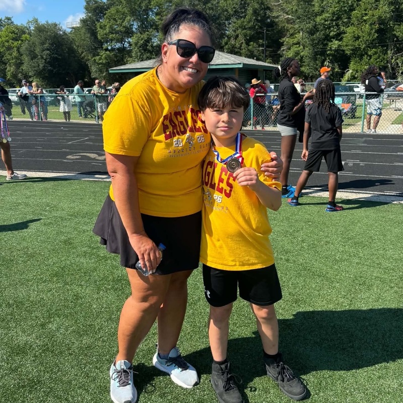 Teacher and Coach, Ms. Wearver stands with her arm around a racer.