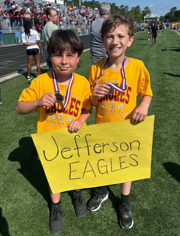 Two boys wearing medals hold a sign that states, "Jefferson Eagles."