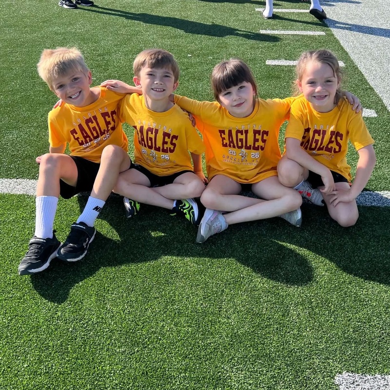 Two boys and two girls sit side-by-side with their arms around each other.