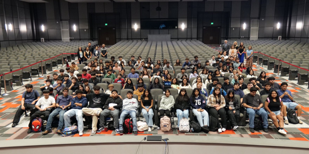 students and adults in large theatre posing for photo