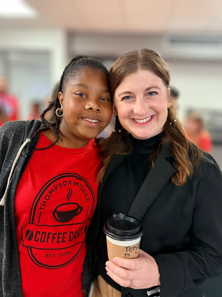 two people posing for photo one of them holding coffee