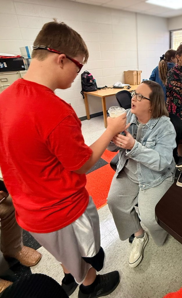 an educator looking pleasantly surprised to receive coffee from a student as part of a school project