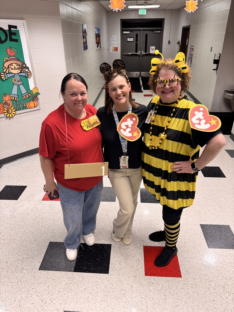 Three teachers standing in the hallway, dressed in Halloween costumes one of them as a bumblebee