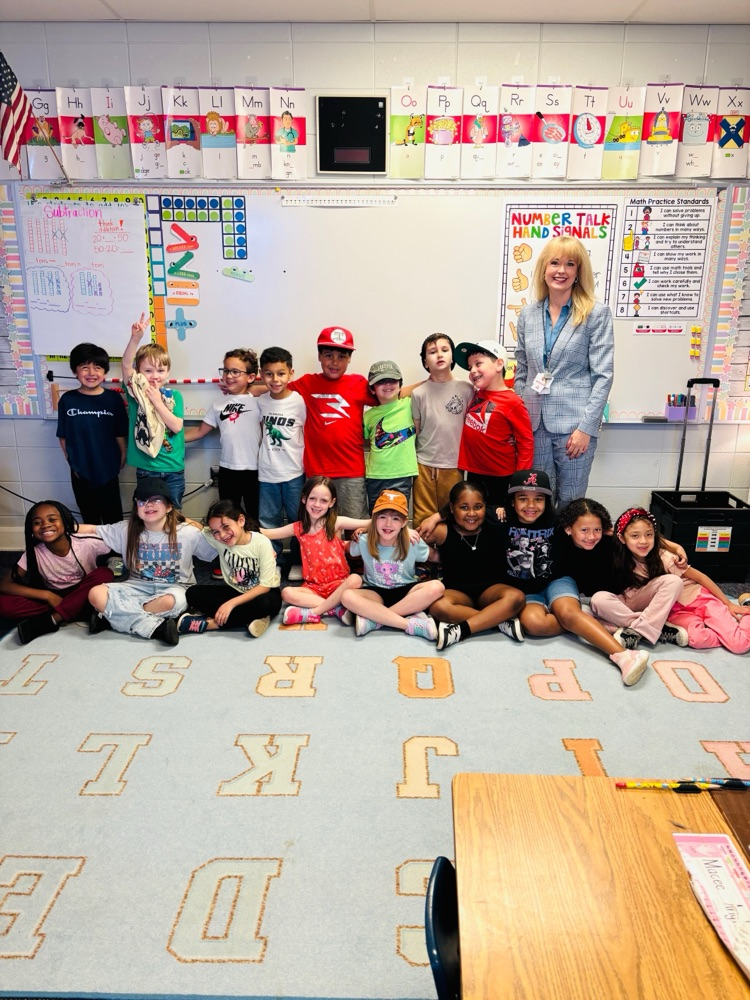 Woman with classroom full of children posing in front of dry erase board