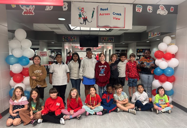 ms weaver's class standing under a read across america sign