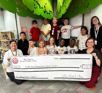 ms. rabu's class with the library giving them the donation check