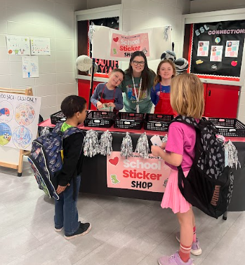 ms. rabu with students selling stickers