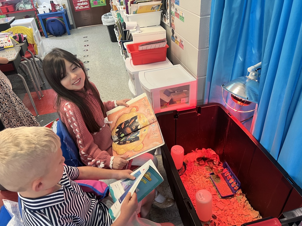 2 students reading to the new chicks and ducks