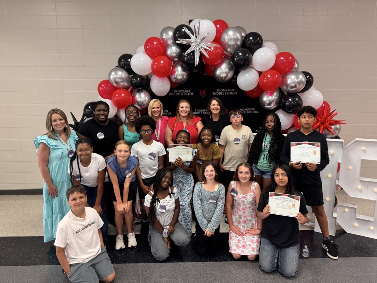 teachers and students in front of balloon arch