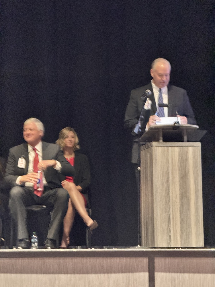 Mann speaking at multiple people sitting on stage