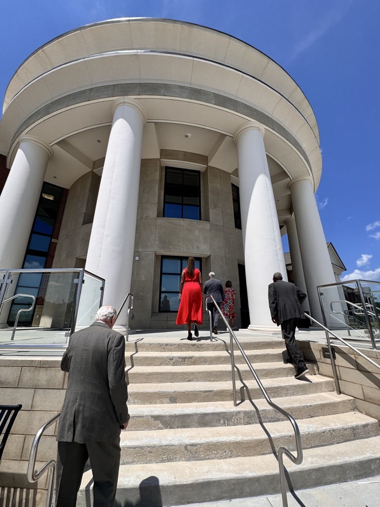 The Grand rotunda at Thompson High high school looking up towards it with a cobalt blue sky, framing it, and people walking up at steps towards White columns