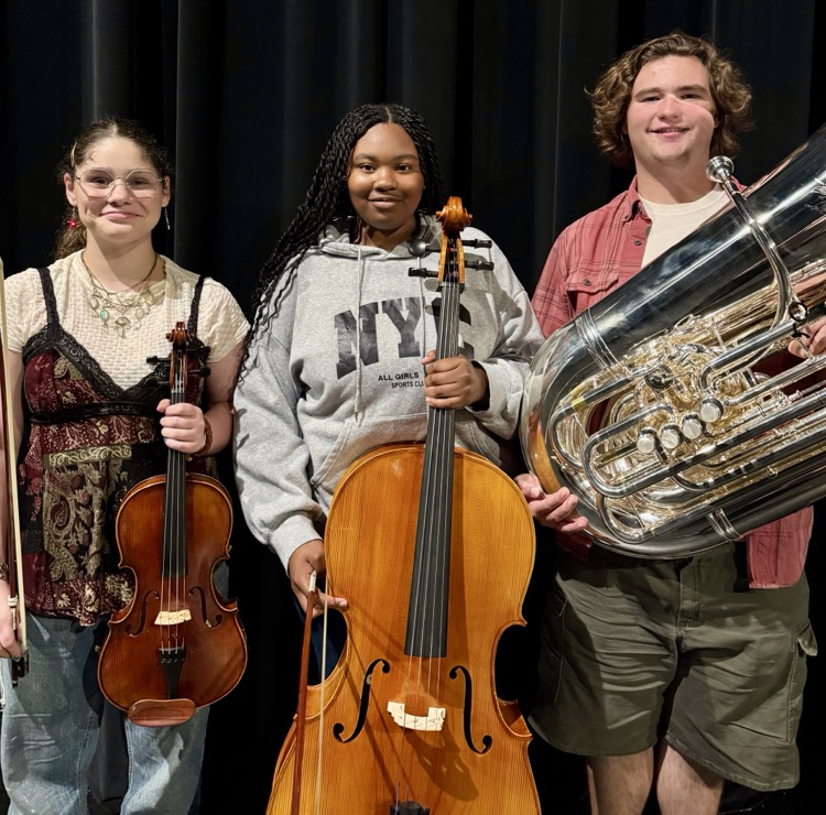 three students holding instruments 